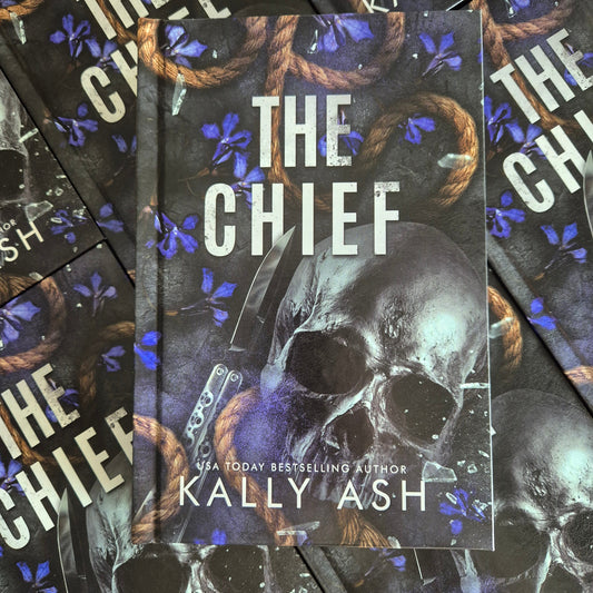 Book titled 'The Chief' by Kally Ash with a skull and butterfly knife design on the cover, surrounded by more books.